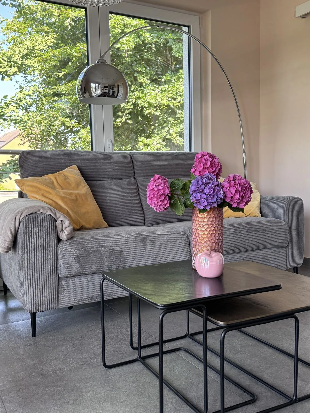 Gemütliches Sofa mit Blumenstrauß und Blick ins Grüne